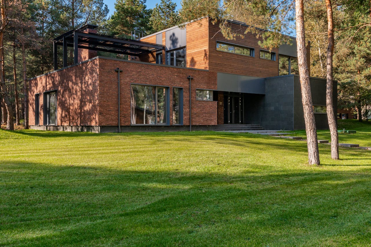 Contemporary house with large windows surrounded by lush greenery and trees.