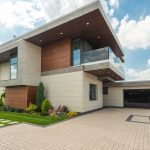 Contemporary luxury house with a sleek design, lush garden, and blue sky.